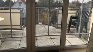A balcony with a glass railing, a chair, and a table. - Hafenstrasse 22 Whg. 7 - Comfortable apartment (Zingst)