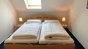 A double bed with a wooden headboard, two bedside tables with lamps, and a skylight above. - Hafenstrasse 22 Whg. 7 - Comfortable apartment (Zingst)