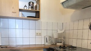 A compact kitchen with wooden cabinets, a built-in oven, and a coffee maker.