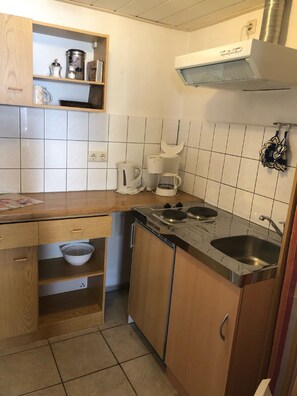 A compact kitchen with a stove, sink, and a coffee maker. - Klosterstrasse 20 ground floor zfw/011 - small, simple vacation accommodation (Zingst)
