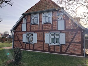 Une maison à deux étages, avec une façade en briques et des volets blancs.