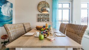 Un comedor con sillas de mimbre, una mesa de madera y un reloj de pared.
