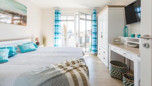 Un dormitorio con cama, escritorio, televisor y vista al exterior.