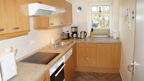 Una cocina compacta con muebles de madera, un lavamanos de acero inoxidable y una ventana con vistas al exterior.