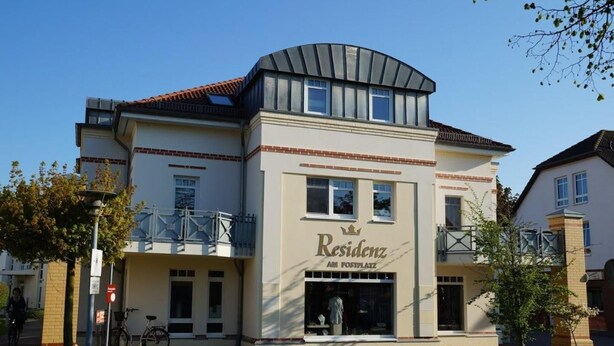 Un edificio de dos pisos con un letrero que dice 'Residenz AM POSTPLATZ'.