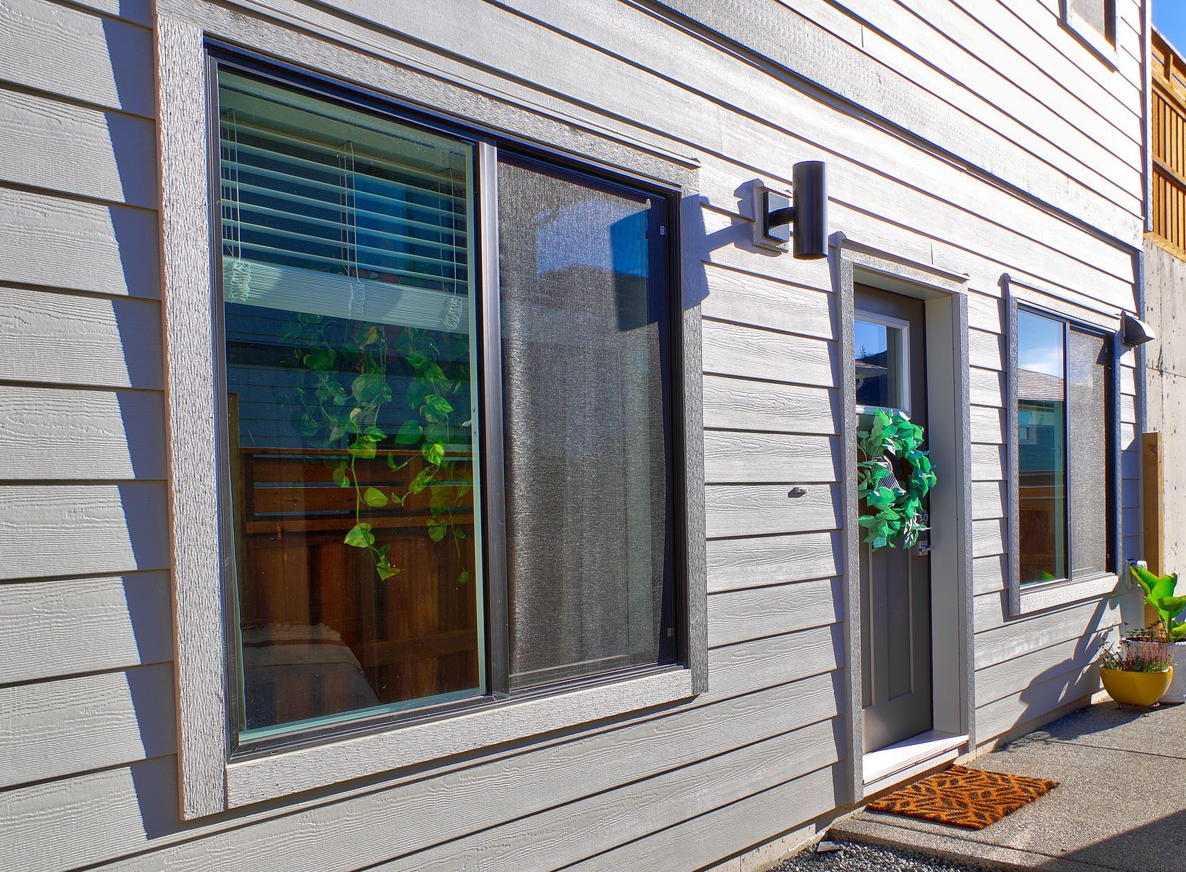 A house with large windows, a door with a wreath, and a potted plant on the porch.