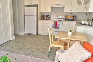 A compact kitchen with a refrigerator, stove, and a dining area with a table and chairs.