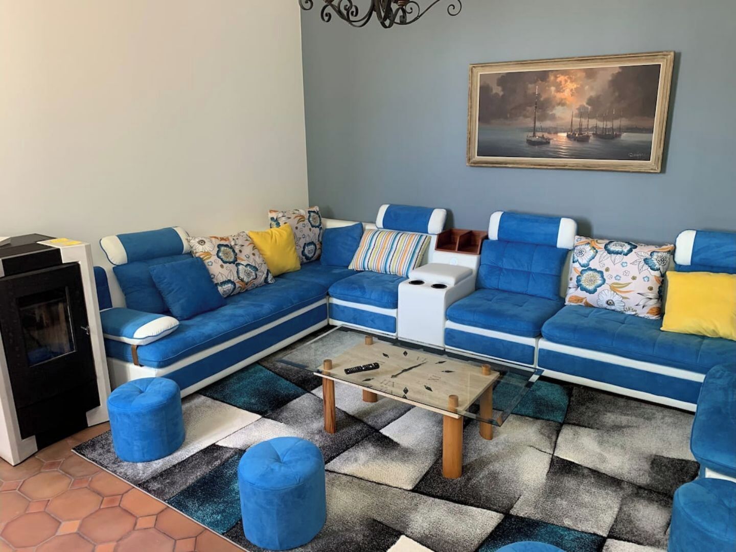 Un salon comprenant un canapé d’angle, des poufs, une table basse et une cheminée.