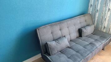 A grey sofa against a blue wall with a vertical striped pattern.