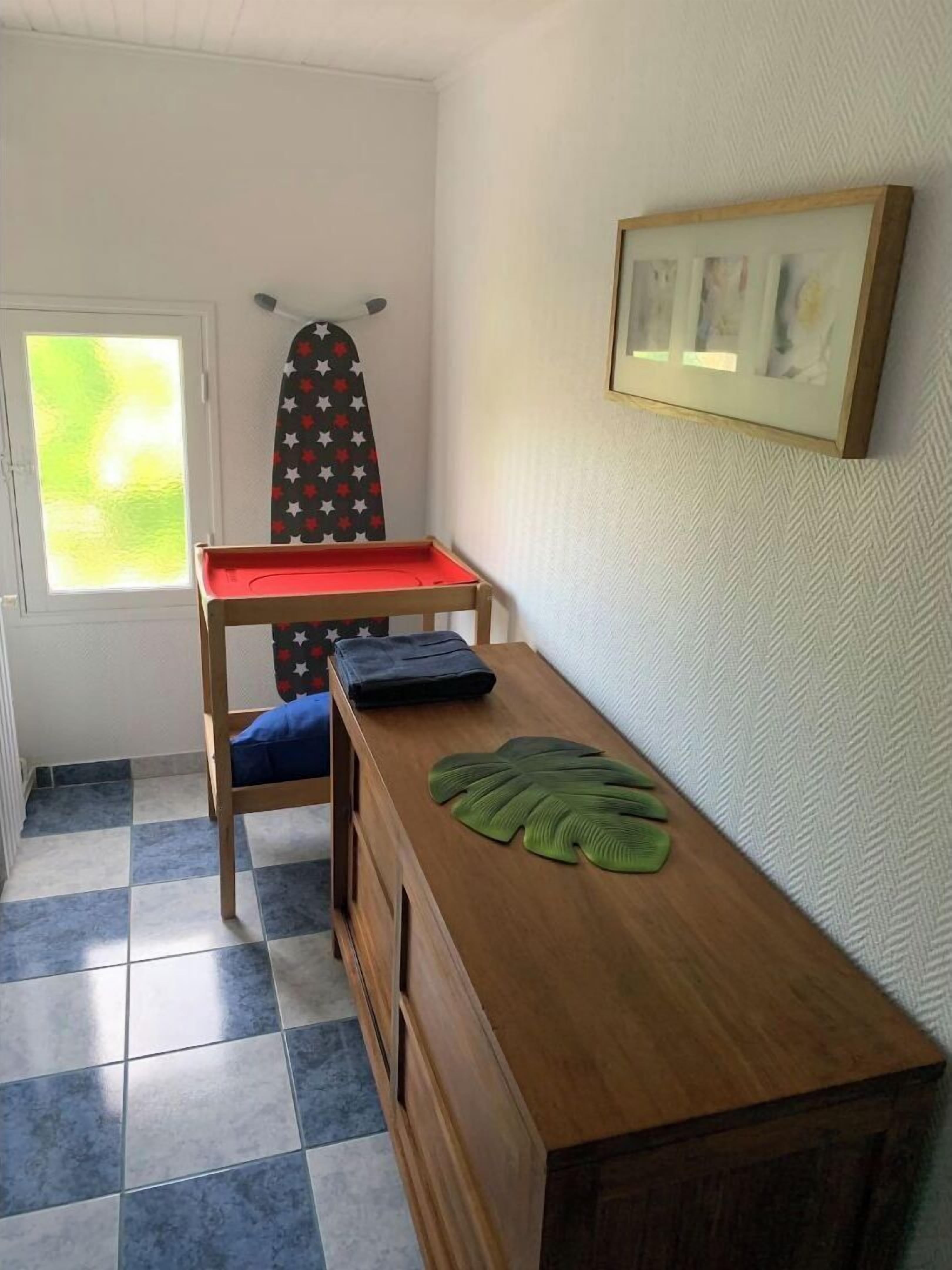 A small room with a wooden desk, a red tray, a blue cushion, and a framed picture on the wall.