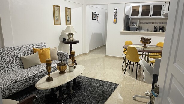 A living room with a sofa, a coffee table, and a dining area with chairs and a table. - Marant's Lodge #2 (Puerto Plata)