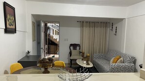 A living room with a dining table, a patterned sofa, and a staircase leading to an upper floor. - Marant's Lodge #2 (Puerto Plata)