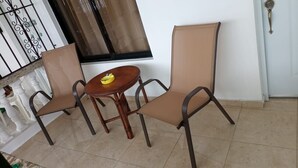 A room with two chairs, a small round table, and a window with a curtain. - Marant's Lodge #2 (Puerto Plata)
