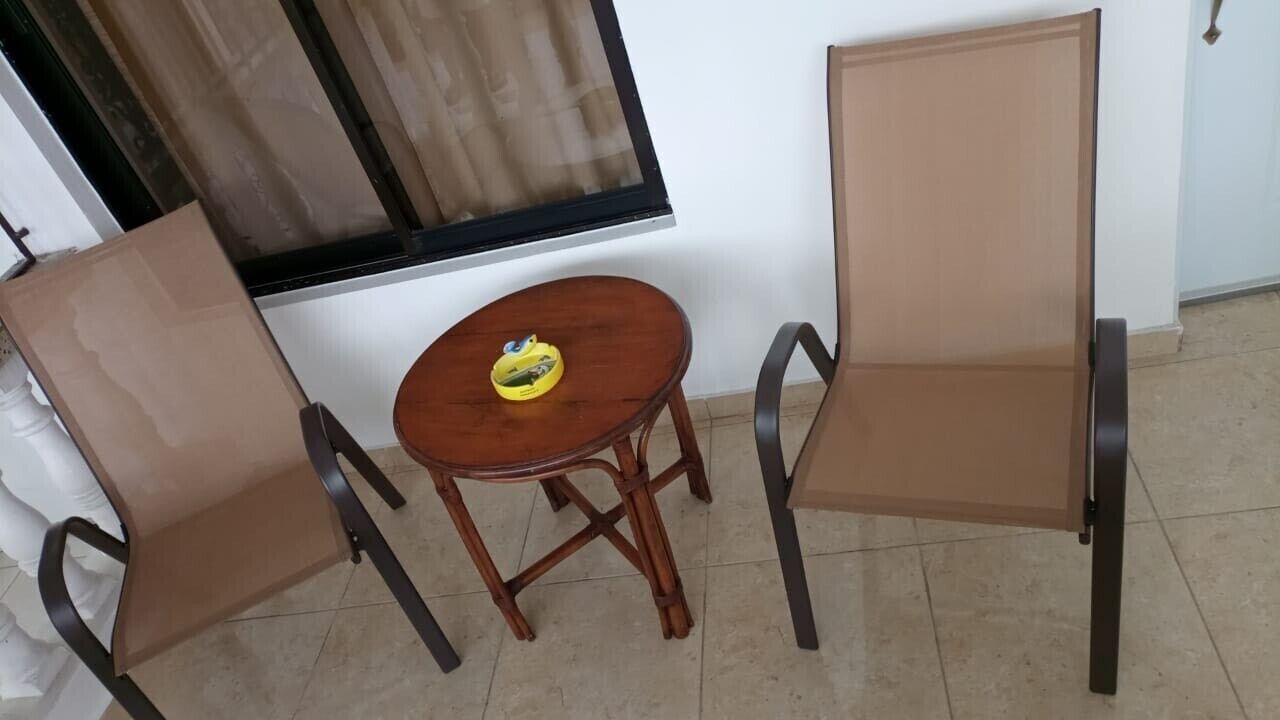 Ein Zimmer mit zwei Stühlen, einem kleinen runden Tisch, einem Fenster mit Vorhängen und einer Tür.