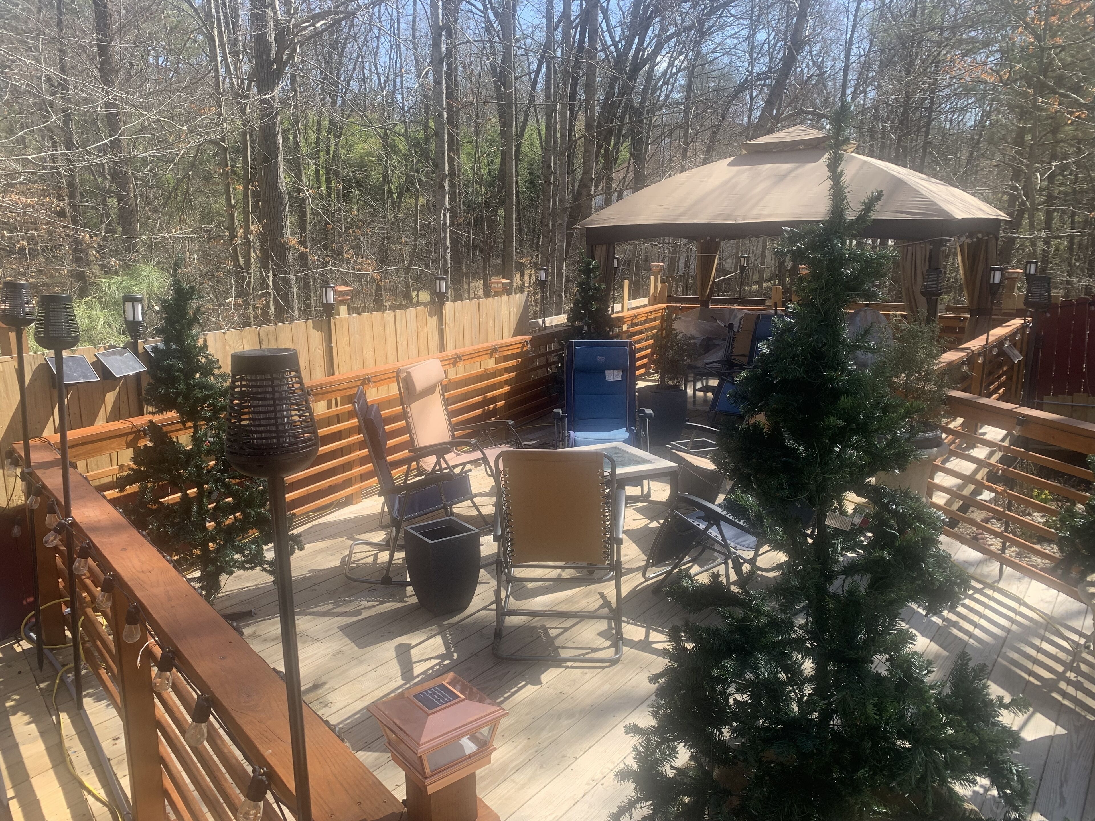 Eine Terrasse mit Sitzgelegenheiten im Freien, ein Pavillon und Weihnachtsbäume.