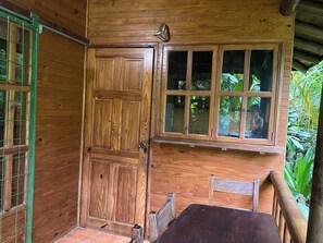 A wooden door with a window, a chair, and a small table. - CASA COLIBRI (Montezuma)