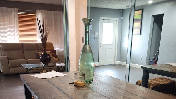 Un comedor con mesa de madera, sillas y un florero.
