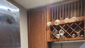 Una cocina con un refrigerador de acero inoxidable, armarios de madera, cafetera y un botellero.