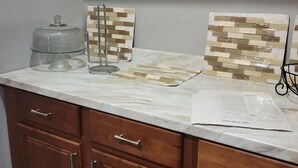 Una cocina con armarios de madera, encimera de mármol y dos paneles decorativos de azulejos.