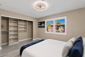 Une chambre Ă coucher comprenant un lit, une grande armoire et deux Ćuvres dâart murales.