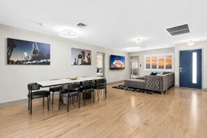 Een moderne woonkamer met een eethoek, een bank en kunstwerken aan de muren.
