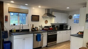 A modern kitchen with white cabinets, a stainless steel stove, and a black countertop.