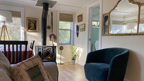 A cozy living room with a sofa, a blue armchair, a fireplace, and a large mirror.