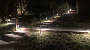 A nighttime outdoor area with steps, stone walls, and illuminated lights.