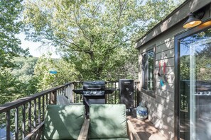 A deck with a grill, outdoor seating, and a water heater.