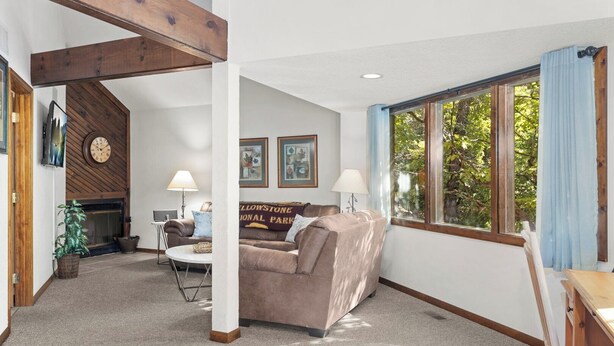 A living room with a couch, two lamps, a fireplace, and a window with curtains.