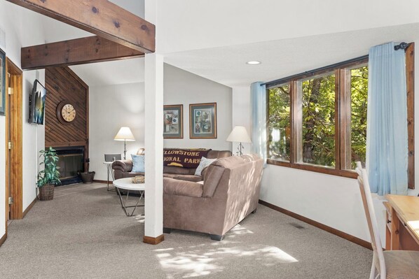 A living room with a couch, two lamps, a fireplace, and a window with curtains.