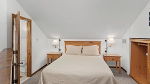 A bedroom with a bed, two bedside tables, a wooden wardrobe, and a door.