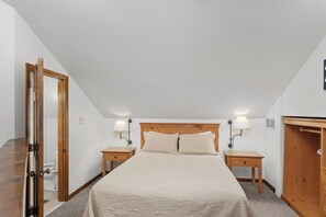 A bedroom with a bed, two bedside tables, a wooden wardrobe, and a door.