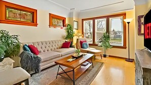 Un salon comprenant un canapé, une table basse et des fauteuils, une cheminée et de grandes fenêtres offrant une vue dégagée.