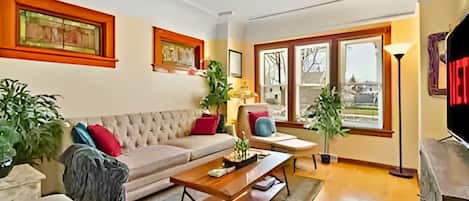 A living room with a sofa, coffee table, and chairs, a fireplace, and large windows with a view.