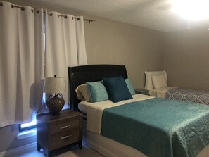 A bedroom with a bed, bedside tables, a lamp, and a curtain. - Spacious 2300SF, Recently Rehabbed, Large Living (Crosby)