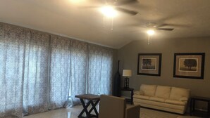 A living room with a sofa, a small table, a lamp, and a ceiling fan. - Spacious 2300SF, Recently Rehabbed, Large Living (Crosby)