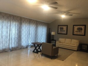 A living room with a sofa, a small table, a lamp, and a ceiling fan. - Spacious 2300SF, Recently Rehabbed, Large Living (Crosby)