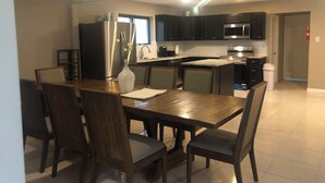 A modern kitchen with dark cabinets, stainless steel appliances, and a dining area with a wooden table and chairs. - Spacious 2300SF, Recently Rehabbed, Large Living (Crosby)