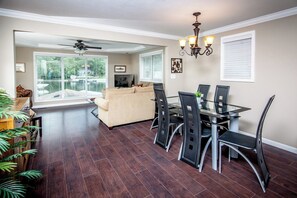 A spacious living area with a dining table, chairs, a sofa, and a ceiling fan.