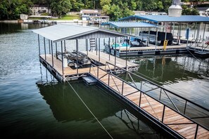 A dock with a covered boat house, a ladder, and a boat.