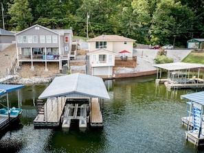 A dock with boats, a house with a covered porch, and a small shed.