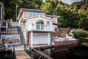 A two-story house with a garage, a dock, and a pond.