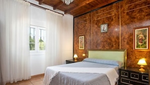 Un dormitorio con una cama grande, paredes de paneles de madera, dos lámparas de noche y una ventana con cortinas.