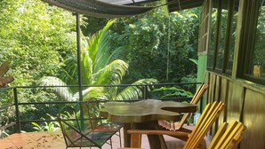 A covered patio area with wooden rocking chairs, a table, and a chair. - CASA EL ARBOL (Provincia de Puntarenas)