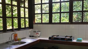 A kitchen with a sink, stove, and a window with a view of greenery. - CASA EL ARBOL (Provincia de Puntarenas)
