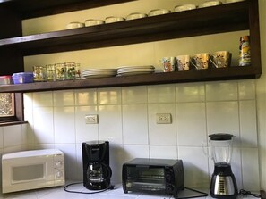 Kitchen area with microwave, coffee maker, toaster oven, blender, and storage.
