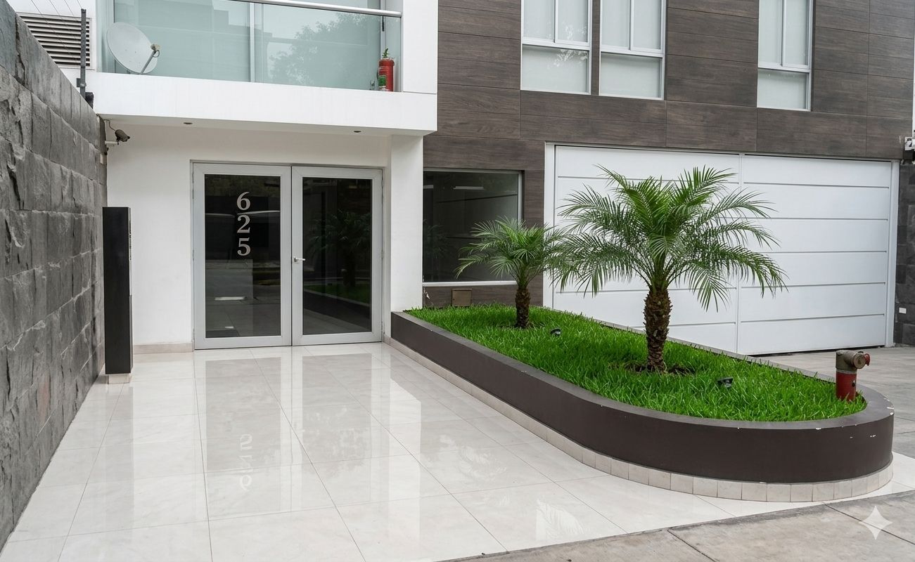 A modern building with a garage door, a stone wall, and a landscaped area with palm trees.