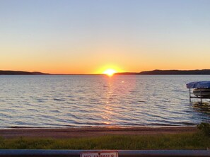 Atardecer sobre un cuerpo de agua tranquilo con un muelle y un letrero que dice "NO ANIMALS".