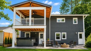 Une maison à deux étages dotée d’un patio couvert, d’un espace salon extérieur et d’un jacuzzi.